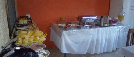 A buffet table with various food items and a refrigerator in the background.