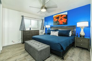A bedroom with a bed, nightstands, a ceiling fan, and a window with curtains.