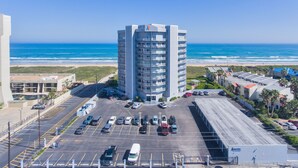 Ein Hochhaus-Hotel mit Parkplatz vor der Tür, mit Blick auf Strand und Meer.
