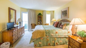 A bedroom with a bed, bedside tables, a dresser, a television, and a window with curtains.