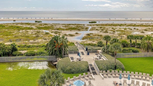 A resort with a pool area, lounge chairs, and a view of the beach and ocean.