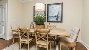 A dining area with a wooden table and chairs, a hanging light fixture, and a framed seascape painting. - Close to Island Amenities (Saint Simons Island)