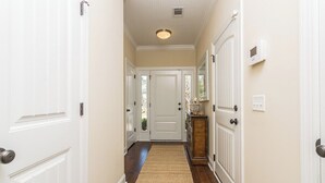 A hallway with white doors, a wooden floor, and a light fixture on the ceiling. - Close to Island Amenities (Saint Simons Island)