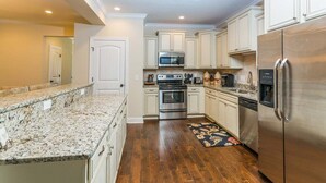 A kitchen with granite countertops, stainless steel appliances, and wooden flooring. - Close to Island Amenities (Saint Simons Island)