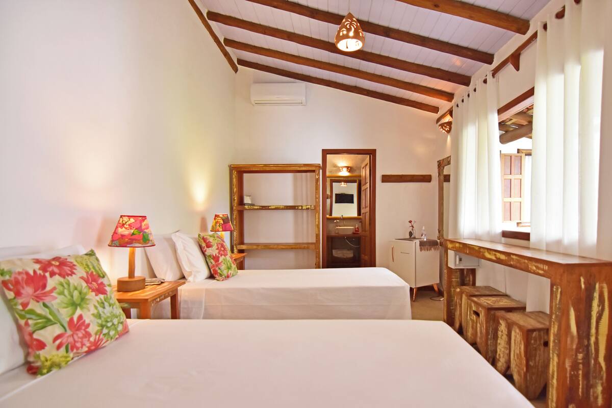 Ein Hotelzimmer mit zwei Betten, Holzbalken an der Decke, einem Schreibtisch und einem Spiegel.