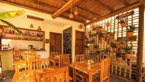 A restaurant with wooden furniture, a chalkboard menu, and potted plants on a wooden partition. - Hostel e Pousada Casa de Paixão (Porto Seguro)
