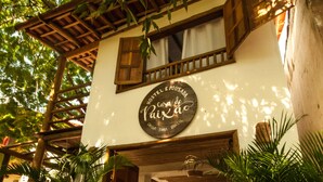 A traditional building with a sign reading "Casa de Paião." It features a wooden balcony, potted plants, and a rustic entrance. - Hostel e Pousada Casa de Paixão (Porto Seguro)