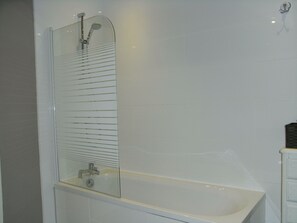 Een bad/douchecombinatie, een haardroger, handdoeken, zeep