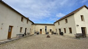 Un patio con suelo de grava, rodeado de edificios con muros de piedra y techos de tejas.
