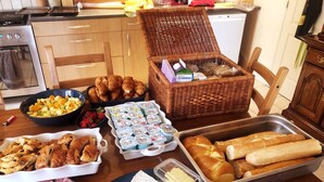 Una mesa con diversos alimentos, incluyendo pasteles, pan, queso y embutidos.
