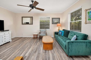 A living room with a green sofa, wooden coffee table, and a ceiling fan.