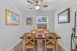 A dining area with a wooden table, four chairs, and a ceiling fan.