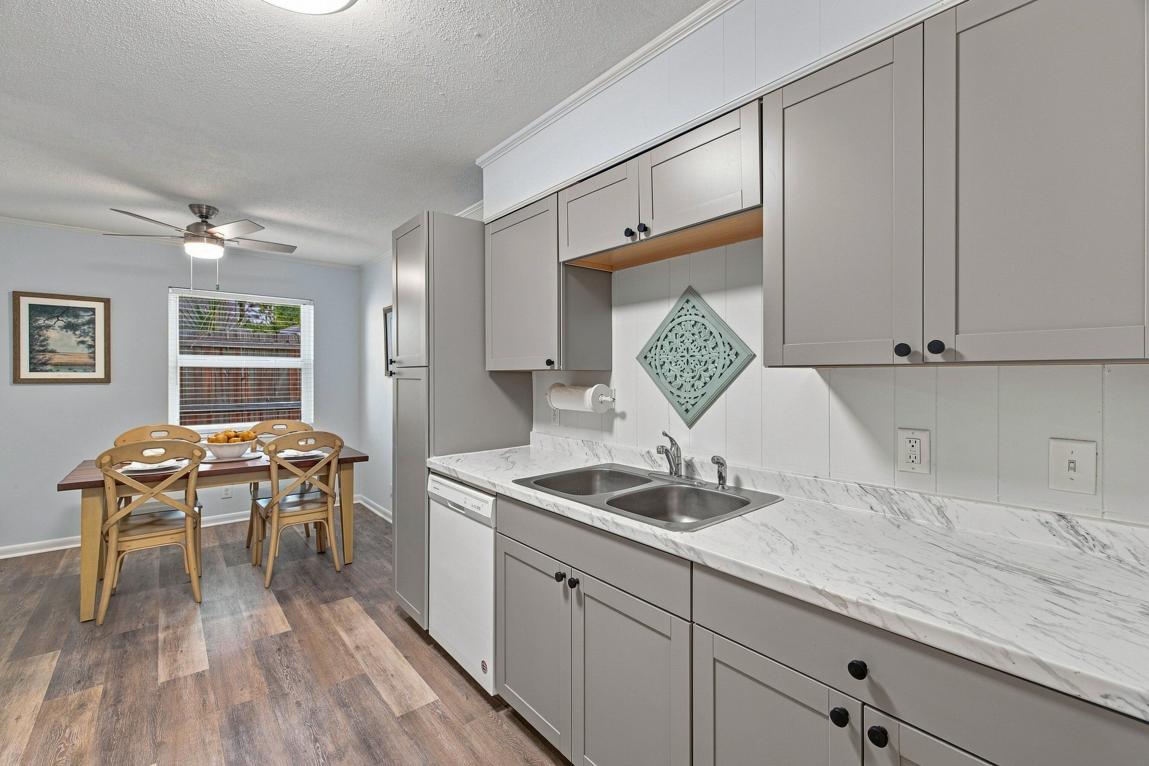 A kitchen with a marble countertop, a built-in sink, and wooden cabinets.