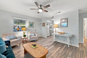 Un salon doté d’un ventilateur de plafond, d’un ensemble de canapés, d’une table basse et d’un coin repas avec une table et des chaises.