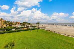 A beach resort with a grassy lawn, palm trees, and a view of the ocean.