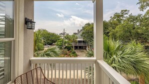 A balcony with a chair, a view of a house, and surrounding greenery. - Feel the Coastal Breeze from your Porch! (Saint Simons Island)