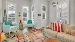 A cozy living room with a beige sofa, a blue armchair, and a colorful rug. - Feel the Coastal Breeze from your Porch! (Saint Simons Island)