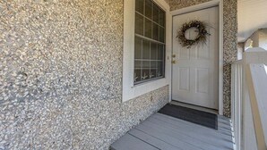Una casa con fachada de piedra, una puerta blanca adornada con una corona y una ventana con rejas.