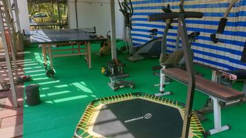 Un gimnasio con diferentes equipos de ejercicio, incluyendo un trampolín, máquinas de pesas y una banca.