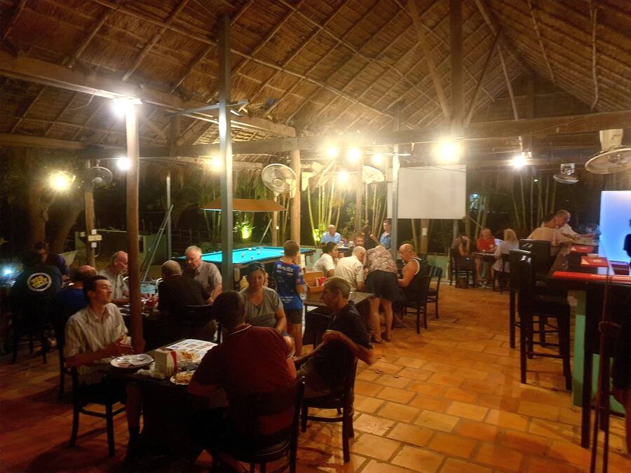 An outdoor dining area with tables and chairs, a pool table, and a projector screen.