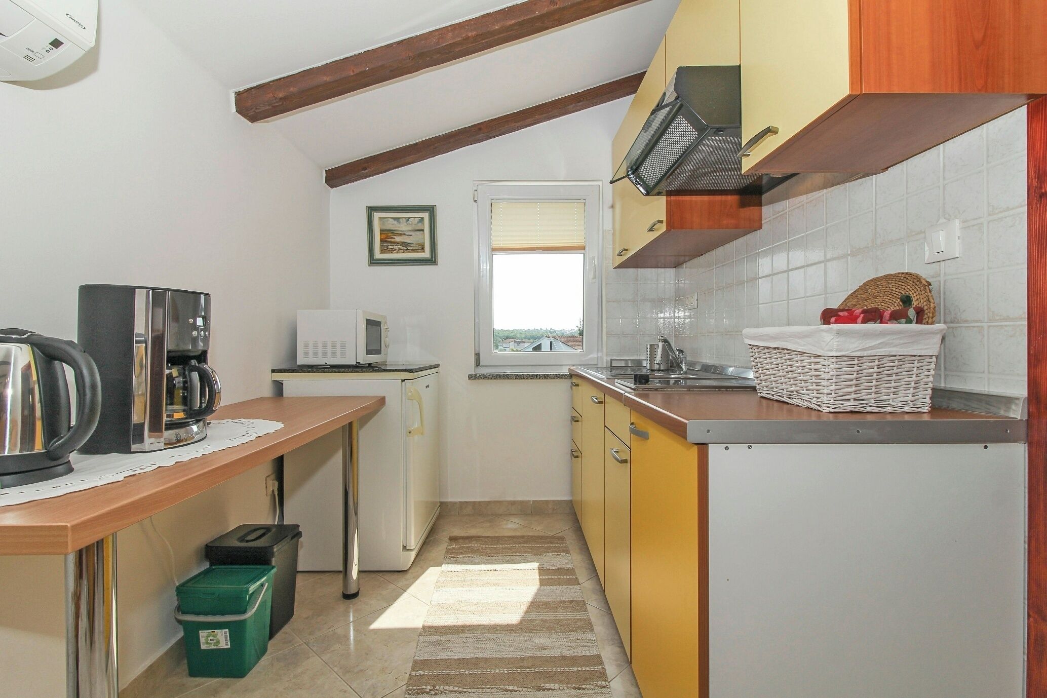 A compact kitchen with a coffee machine, a microwave, and a sink.