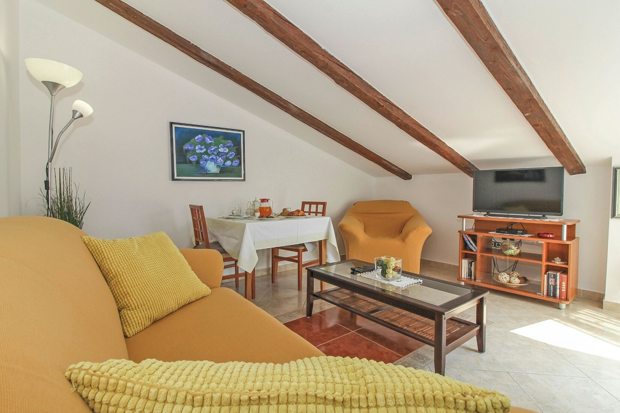 Ein Wohnzimmer mit Sofa, Sessel, Couchtisch und einer TV-Konsole mit Regalen.