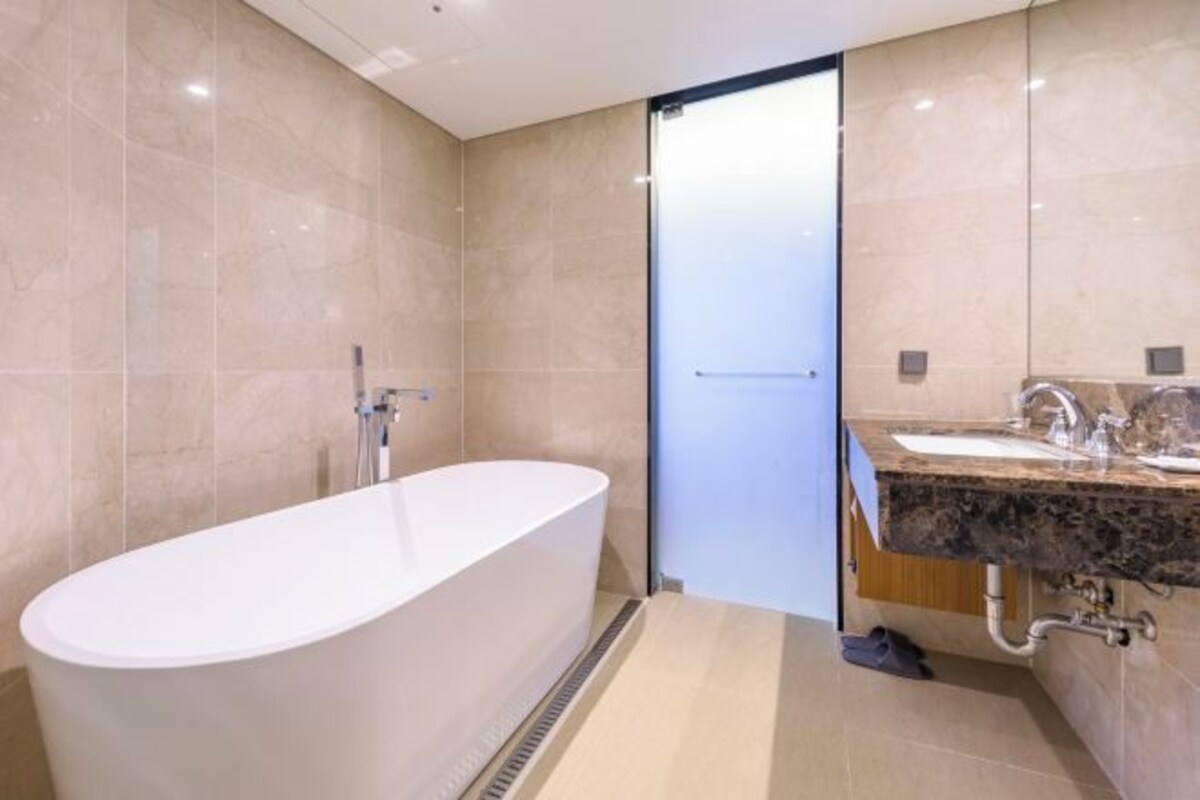 A modern bathroom with a freestanding bathtub, a sink with a marble countertop, and a glass shower enclosure.