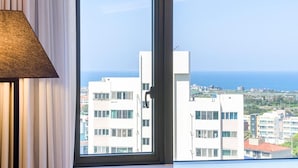 Une pièce dotée d’une grande fenêtre donnant sur un paysage urbain et la mer.