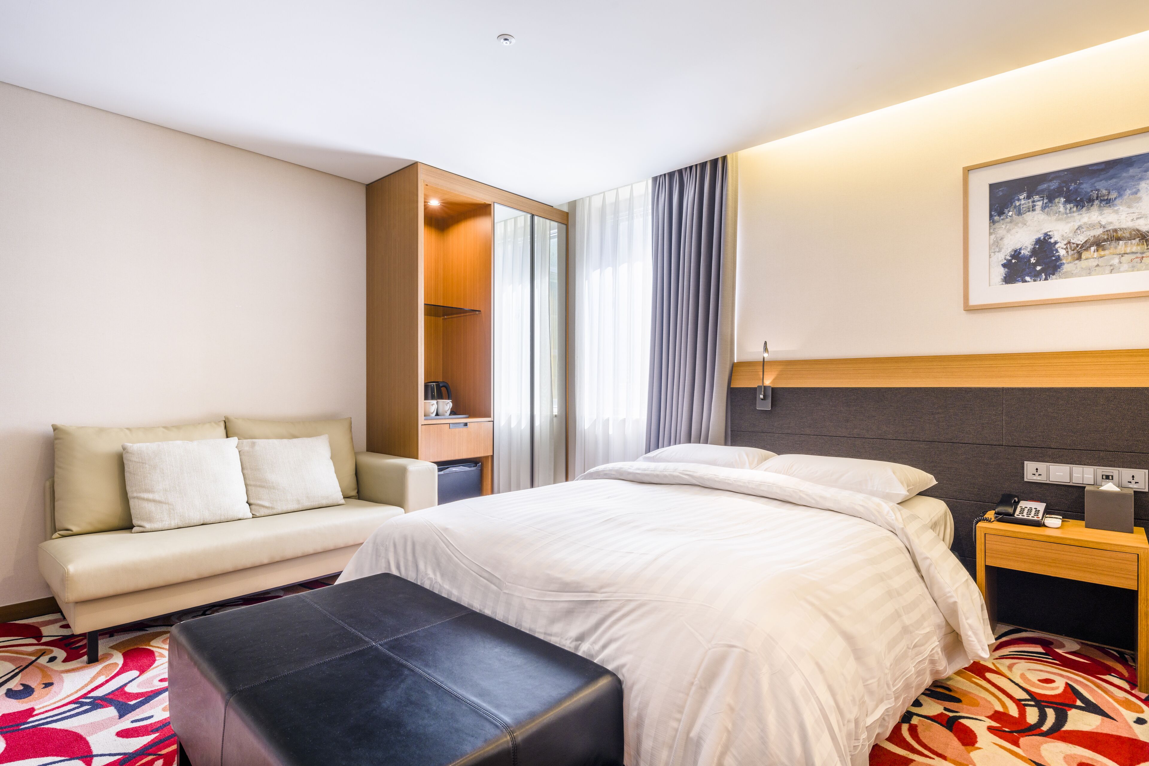 Una habitación de hotel con cama, sofá, una mesita y escritorio.