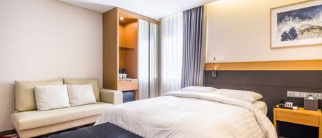Una habitación de hotel con cama, sofá, una mesita y escritorio.