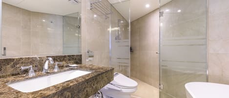 A modern bathroom with a granite countertop, a white sink, a toilet, and a glass-enclosed shower area.