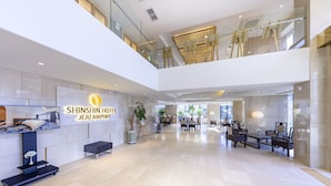 Un hall d’entrée spacieux comprenant un comptoir d’accueil, un espace détente et un panneau indiquant l’hôtel Shinshin, situé près de l’aéroport de Jeju.