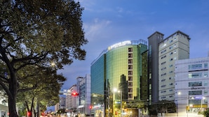 Un hôtel moderne doté d’une façade en verre, de plusieurs étages et d’une enseigne bien visible.