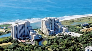 Un hotel de gran altura con varios pisos, un estacionamiento y vistas a la playa y al océano.