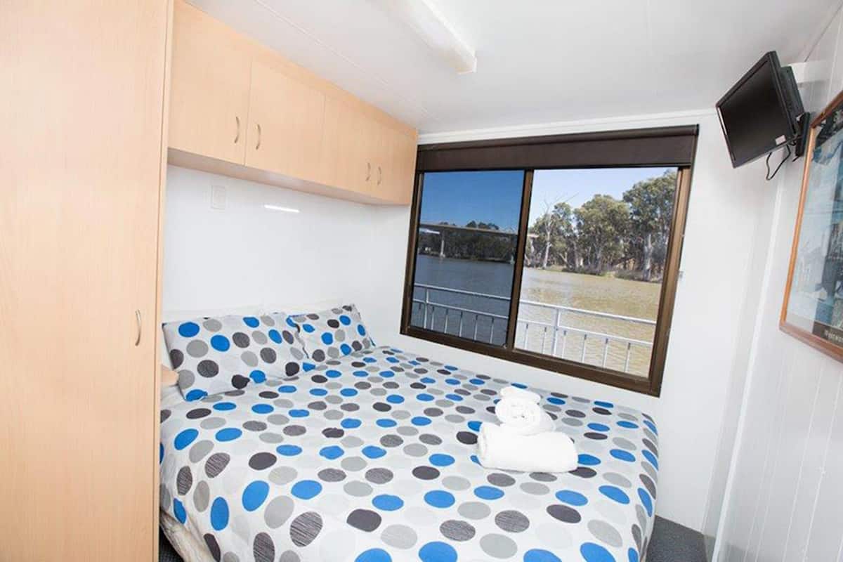 Une chambre avec un lit, une fenêtre donnant sur un beau paysage, une télévision et une armoire.