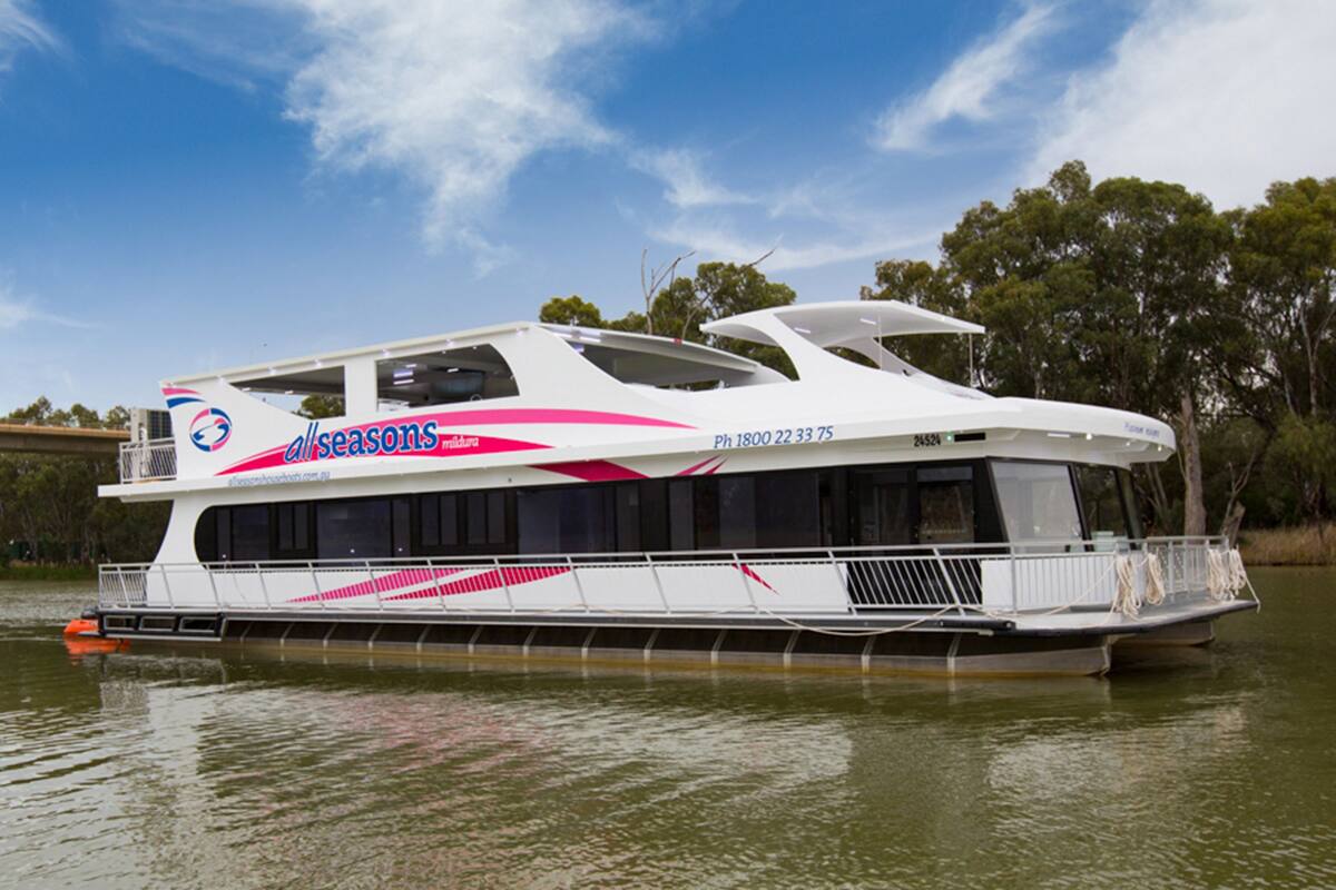 Un grand navire de croisière moderne, à la coque blanche et aux touches roses, doté d’un pont spacieux et de nombreuses fenêtres sur le côté.