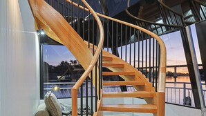 Una scala a chiocciola in legno con ringhiere in metallo, che conduce a un balcone con vista sulla città.