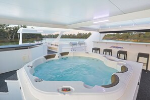 A hot tub with a control panel, a seating area, and a view of the water. - All Seasons Houseboats (Mildura)