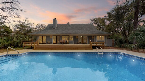 Een huis met een zwembad, een terras en een groot raam met uitzicht op het zwembad.