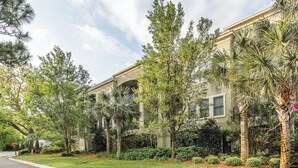 A residential building with a well-maintained lawn, palm trees, and a stop sign. - Located just blocks from Oceanfront Neptune Park (Saint Simons Island)
