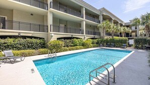 A multi-story hotel with a swimming pool, outdoor seating, and palm trees. - Located just blocks from Oceanfront Neptune Park (Saint Simons Island)