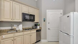 A kitchen with beige cabinets, a microwave, a dishwasher, and a refrigerator. - Located just blocks from Oceanfront Neptune Park (Saint Simons Island)
