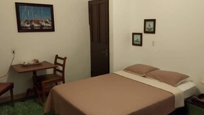 A room with a bed, a desk, a chair, and a door. - Lasa Residence (Oranjestad)