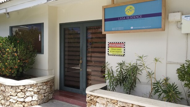 A building entrance with a sign for "Lasa Residence" and a private parking sign. - Lasa Residence (Oranjestad)
