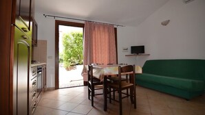 Un espacio habitable compacto con kitchenette, comedor y sofá verde.