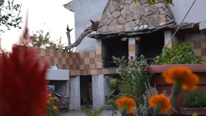 Un patio con una construcción de piedra, plantas en macetas y flores naranjas.