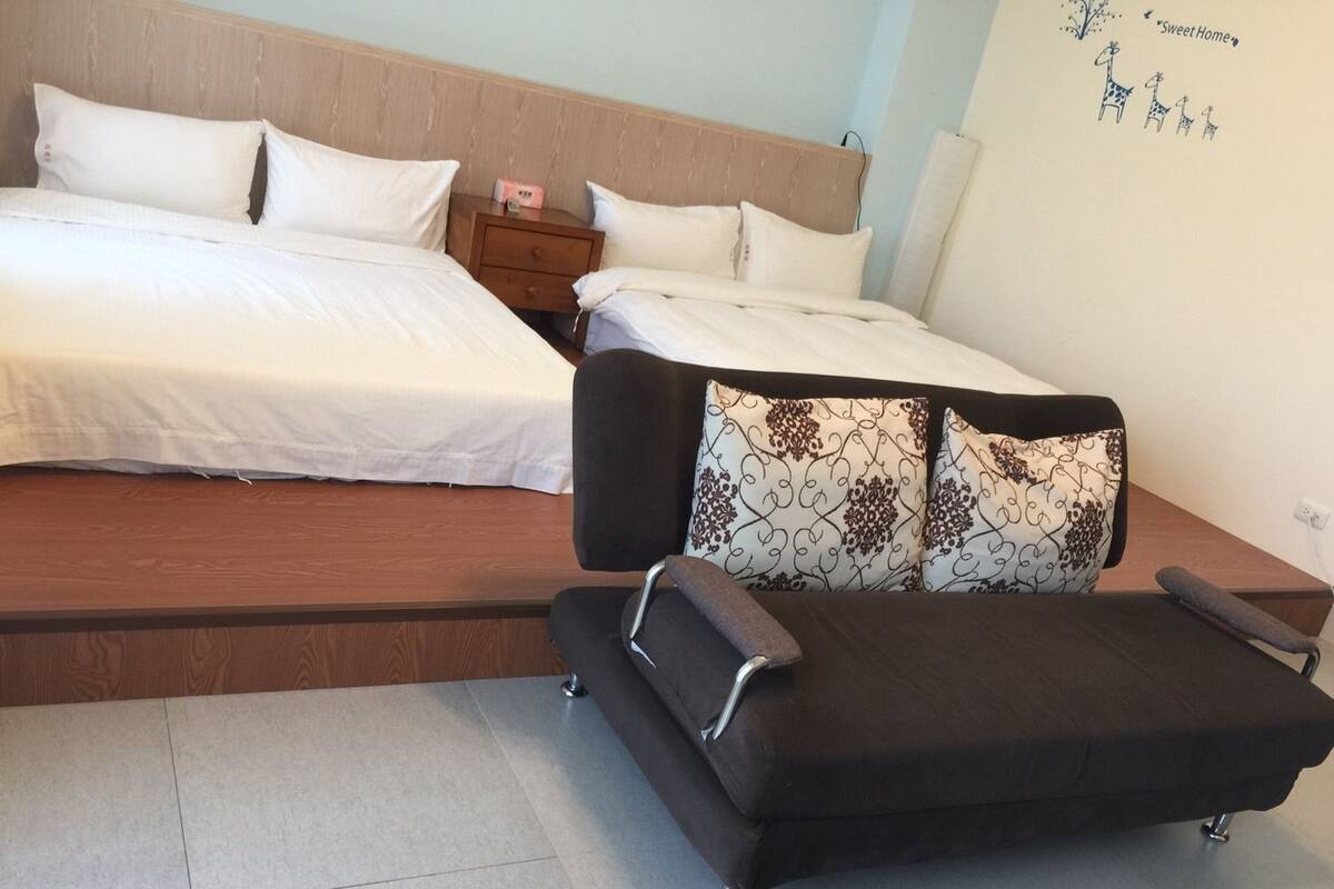 A bedroom with a bed, a nightstand, a chair, and a wall decoration.