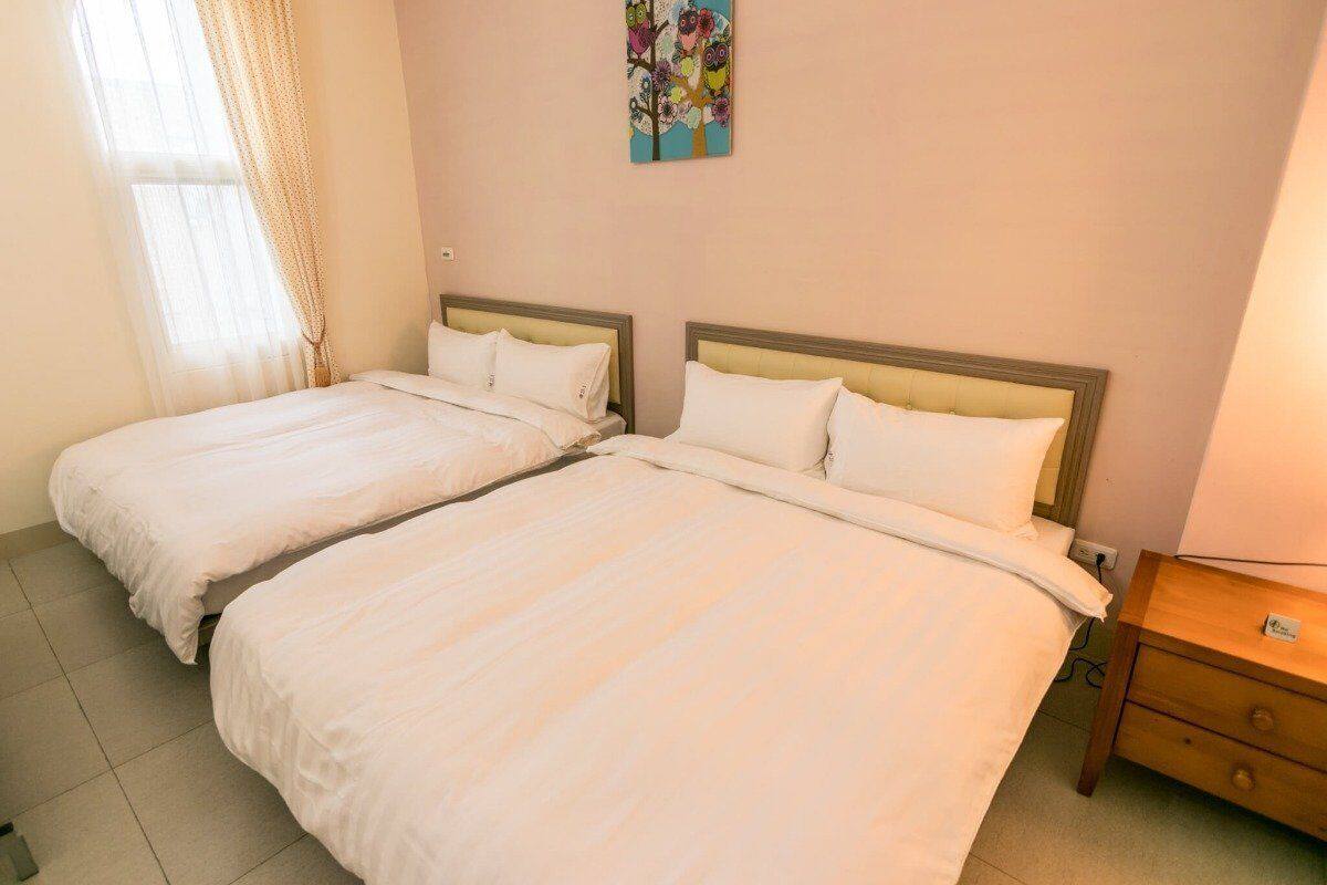 A hotel room with two beds, a nightstand, and a painting on the wall.