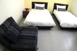 A hotel room with a sofa, two beds, and a small table with fruit. - Ruisui 38 Homestay (Ruisui)