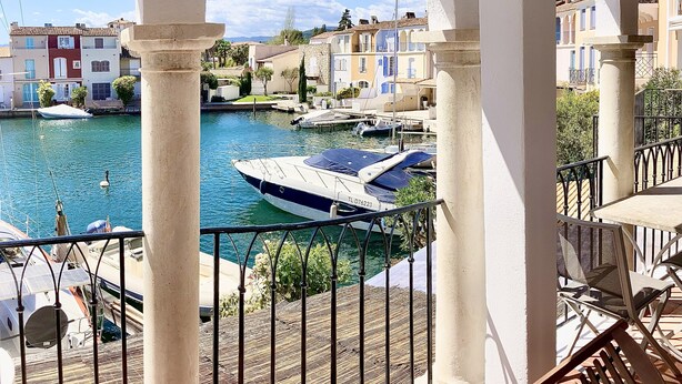 Un balcon avec vue sur un port de plaisance, des bateaux et des bâtiments aux couleurs vives.